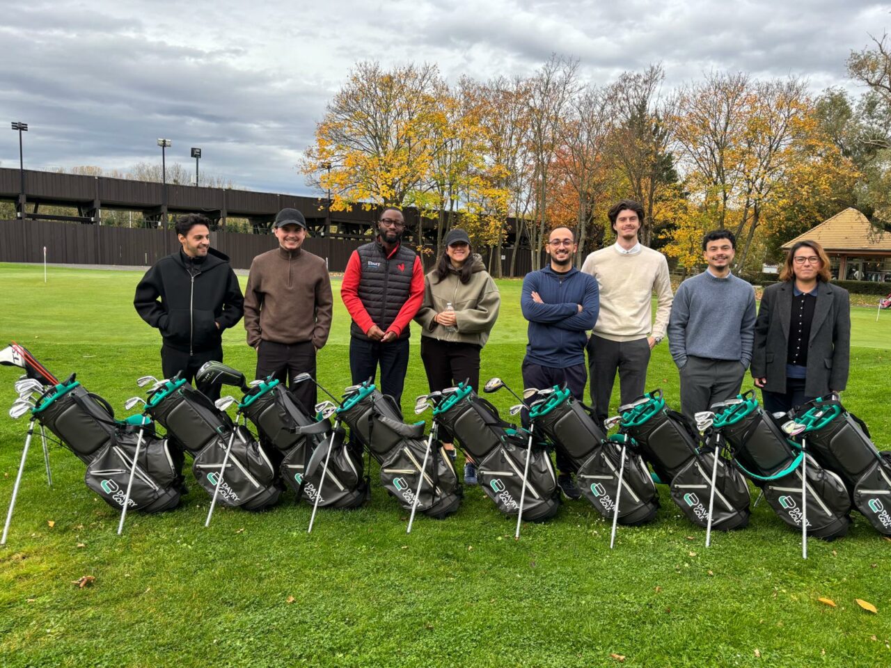 Équipe en formation DavryGolf debout derrière une rangée de sacs de golf DavryGolf