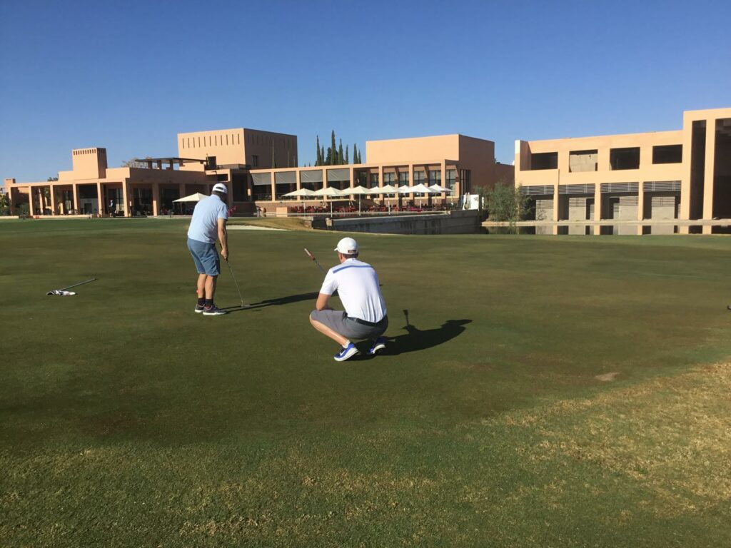 Golfeur lisant la ligne de putt devant le club-house pendant un stage de golf