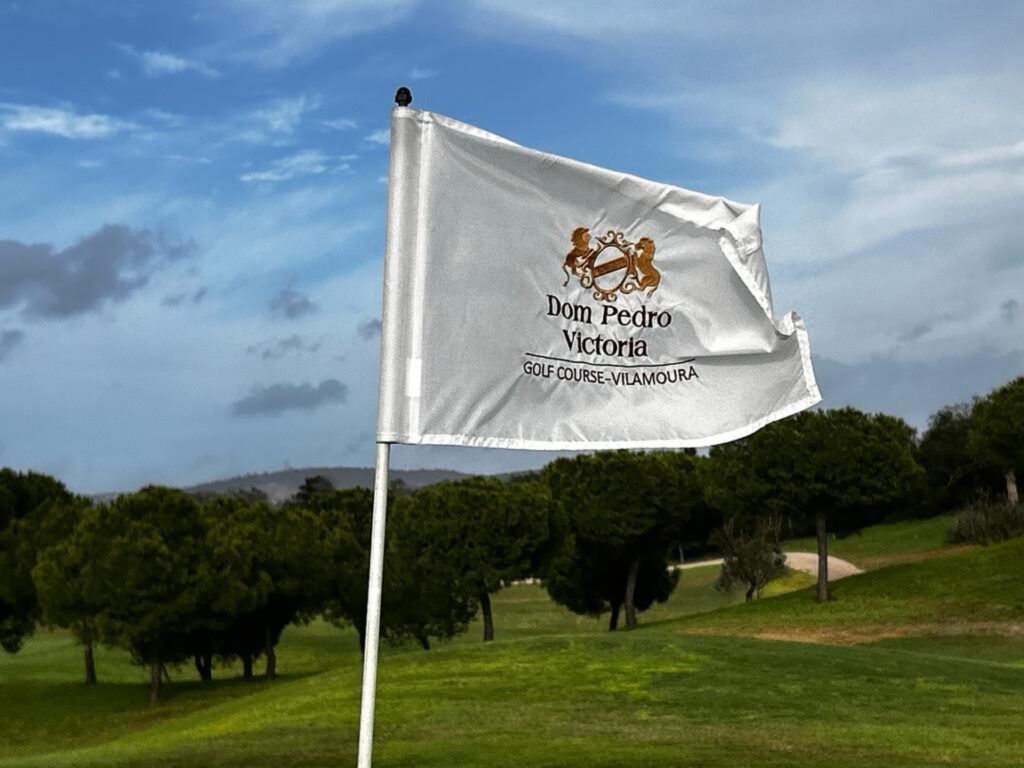 Drapeau du Dom Pedro Victoria Golf Course à Vilamoura, devant un parcours bordé de pins