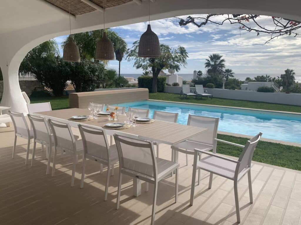 Grande table d'extérieur sous une arche, piscine et mer