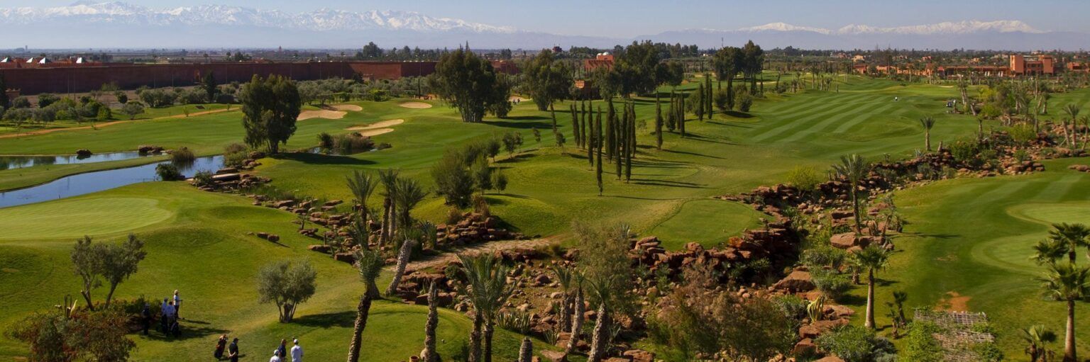 Un fairway de l'Atlas Golf Marrakech bordé d'un plan d'eau et de palmiers