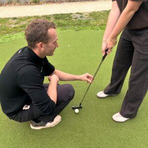 Edouard Davry corrige la prise de club d'une élève pendant un cours de golf au Coudray-Montceaux
