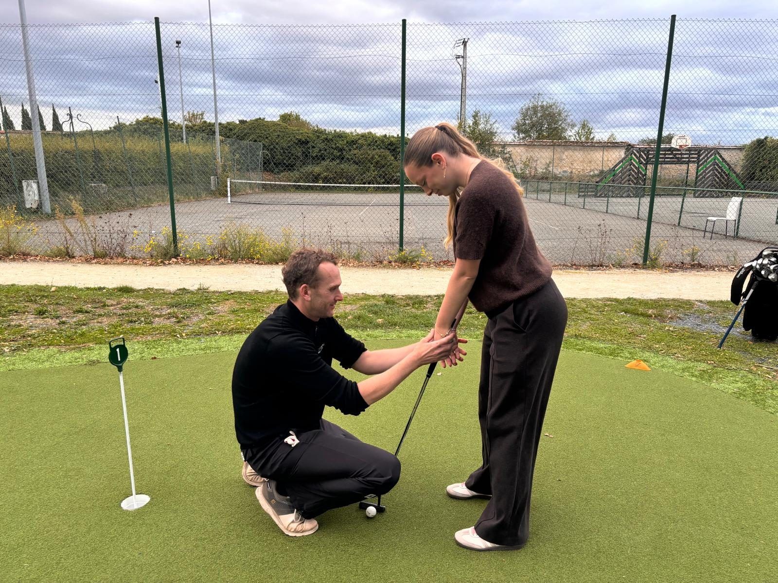 Edouard Davry ajuste la prise de putter d'une élève sur le putting green du Parc du Coudray